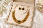 Gold-tone short necklace with green centre stone and matching earrings in an ivory jewellery box